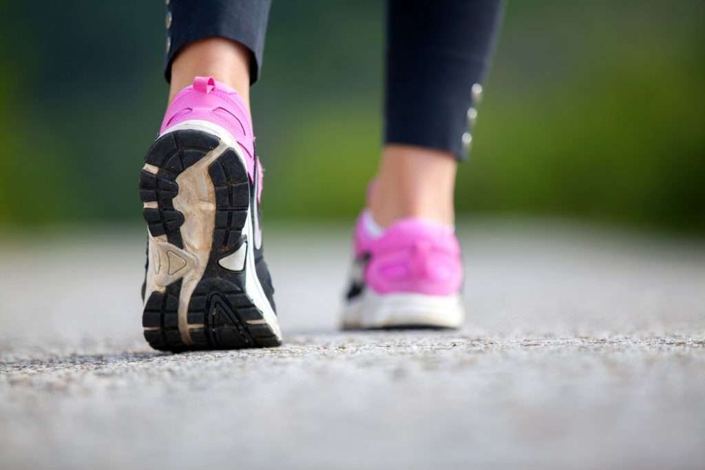 Close-up of pink sneakers walking on pavement