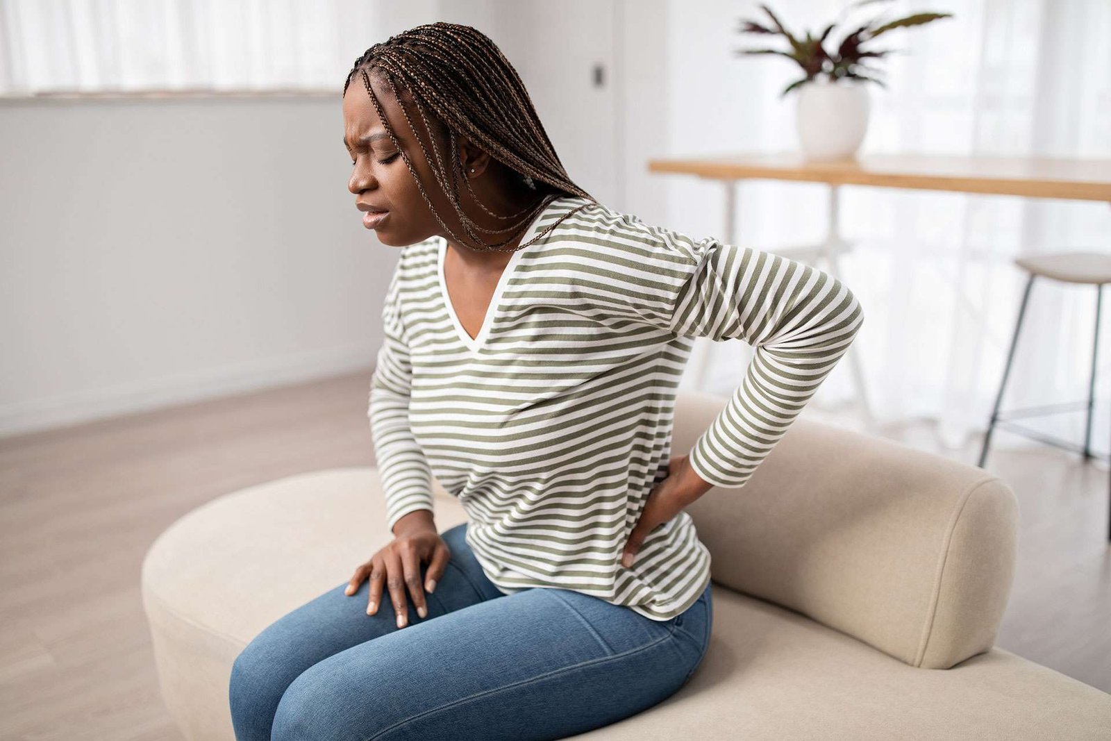 Woman with back pain sitting on couch