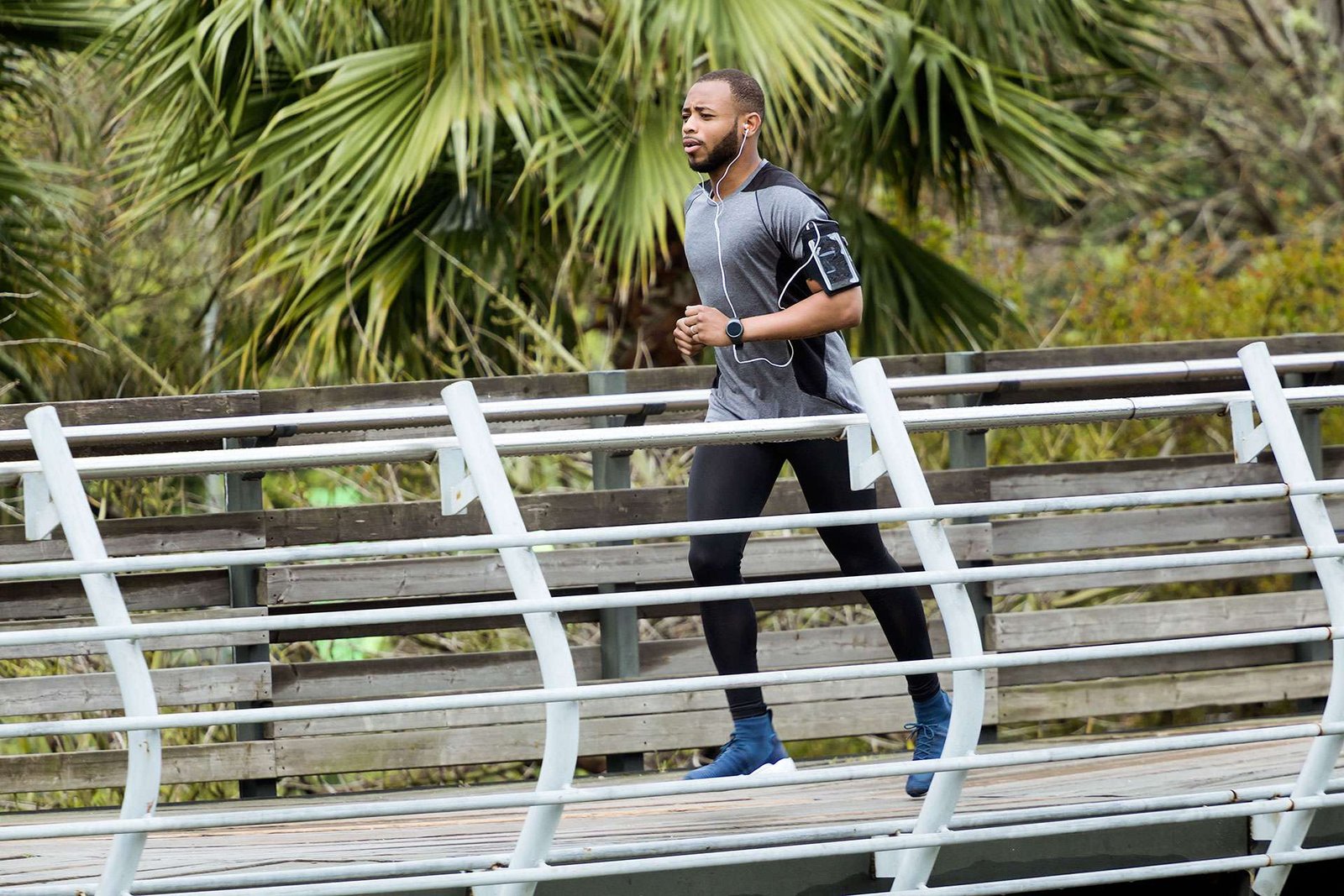 Man jogging on bridge with earphones in park