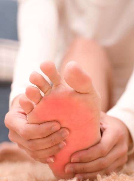 Person massaging sore foot with red inflammation