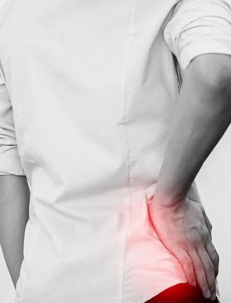 Person in white shirt holding painful lower back