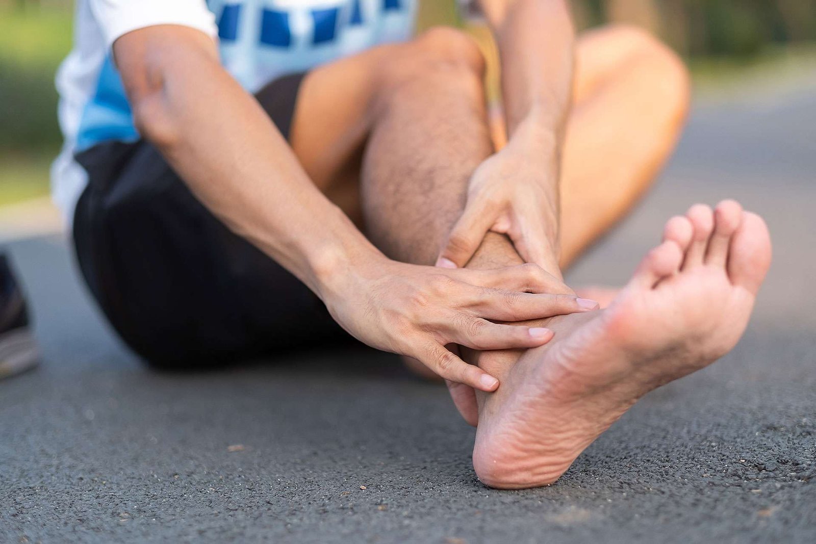Runner holding injured foot on pavement